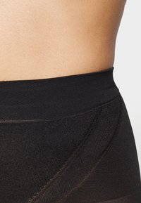 Schwarzer Bund der formenden Shorts, mit einer glatten Textur und dezenten Nähten. Das Material wirkt dehnbar und enganliegend.