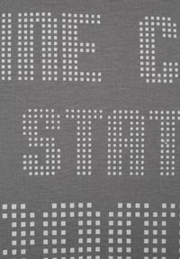 Grått tyg med texturerad vit text gjord av små fyrkanter, som visar ord i ett rutmönster över ytan.