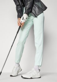 Ανοιχτό μπλε γκολφ παντελόνι με στενή εφαρμογή και κωνικό πόδι, σε συνδυασμό με λευκά γκολφ παπούτσια με γκρι λεπτομέρειε�ς και σχέδιο με κορδόνια.