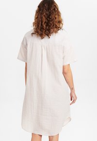Gestreiftes Baumwollkleid in hellem Beige und Weiß, mit kurzen Ärmeln, einem Rückenpasse und einem abgerundeten Saum mit Seitenschlitzen.