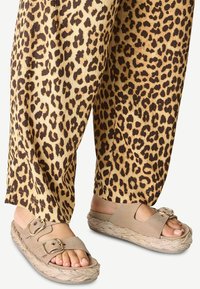 Beige platform sandals with two adjustable buckles, paired with light brown leopard print pants featuring textured fabric and a loose fit.