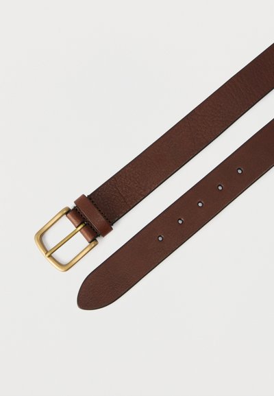 Ceinture en cuir marron avec une boucle en laiton et cinq trous de réglage sur un fond blanc.