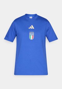 Tricou albastru cu mâneci scurte, din bumbac. Are guler tip rond, logo adidas auriu și un ecuson de fotbal cu steagul Italiei și patru stele.