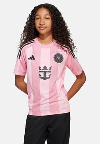 Maillot de football rose avec des rayures verticales, accents noirs, col rond et logo comportant une couronne. Manches courtes, tissu en mesh pour une meilleure respirabilité.