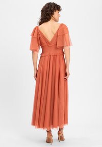 Stofroze jurk met gelaagde doorzichtige mouwen, smock taille en vloeiende rok. V-back ontwerp benadrukt door zachte stoftextuur.