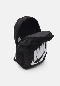 Zaino Nike nero con un grande logo bianco, dotato di un compartimento principale con cerniera e tasche laterali in rete per una maggiore capacità di conservazione.