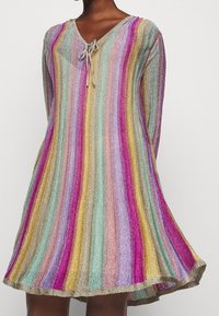 Abito corto e multicolore con strisce verticali in toni pastello e metallici, caratterizzato da un scollo a V e un dettaglio con fiocco all'escollatura.