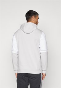 Lysegrå hættetrøje med en hvid frontpanel og hætte, der har en blød tekstur, lange ærmer og et enkelt design uden synlige logoer.