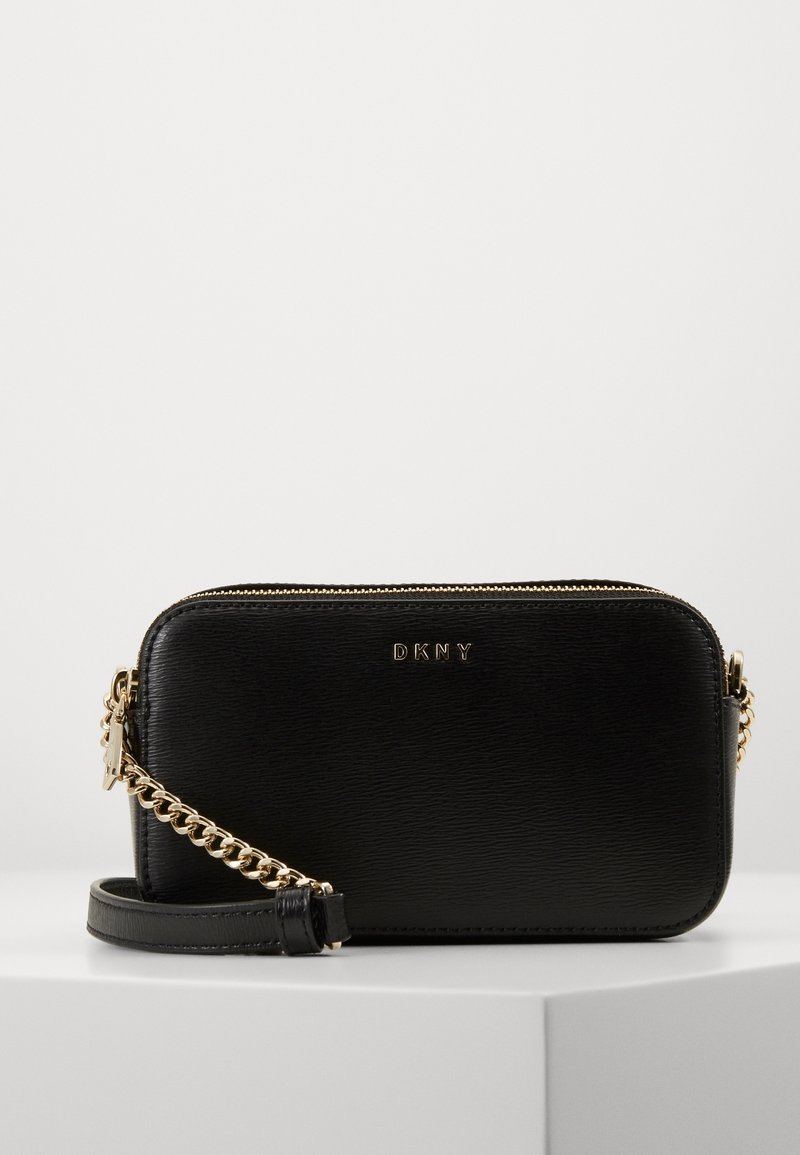 Černá kožená crossbody taška s texturovaným povrchem, zlatým řetízkovým popruhem a zipovým uzavřením. Na přední straně je embosované logo.