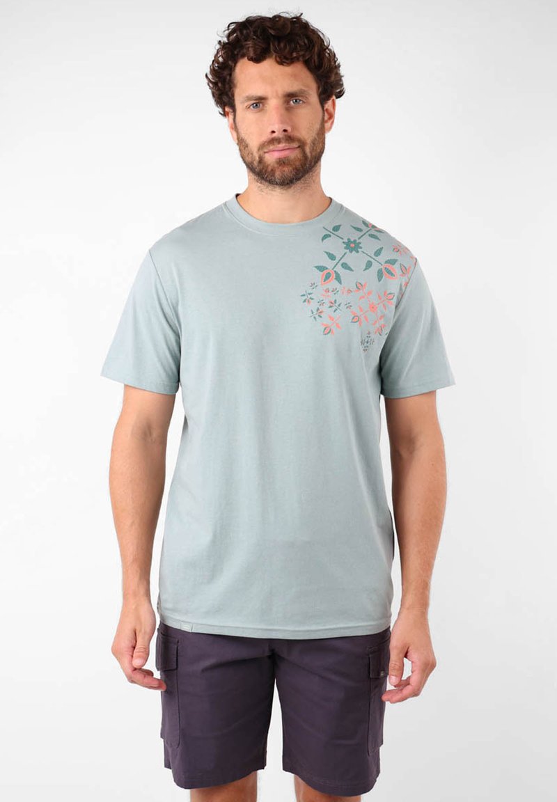 T-shirt en coton bleu clair avec des impressions florales orange et bleu-vert sur l'épaule gauche ; col rond ; manches courtes ; coupe décontractée.