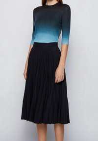 Pletený top v gradientu modré do černé, spojený s černou plisovanou sukní. Sukně má vysoký pas a vzdušný design pro snadnost pohybu.