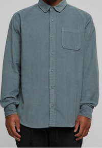 Lange mouw button-up shirt in gedempt teal corduroy, met een enkele borstzak, een button-down kraag en subtiele ribbelstructuur.