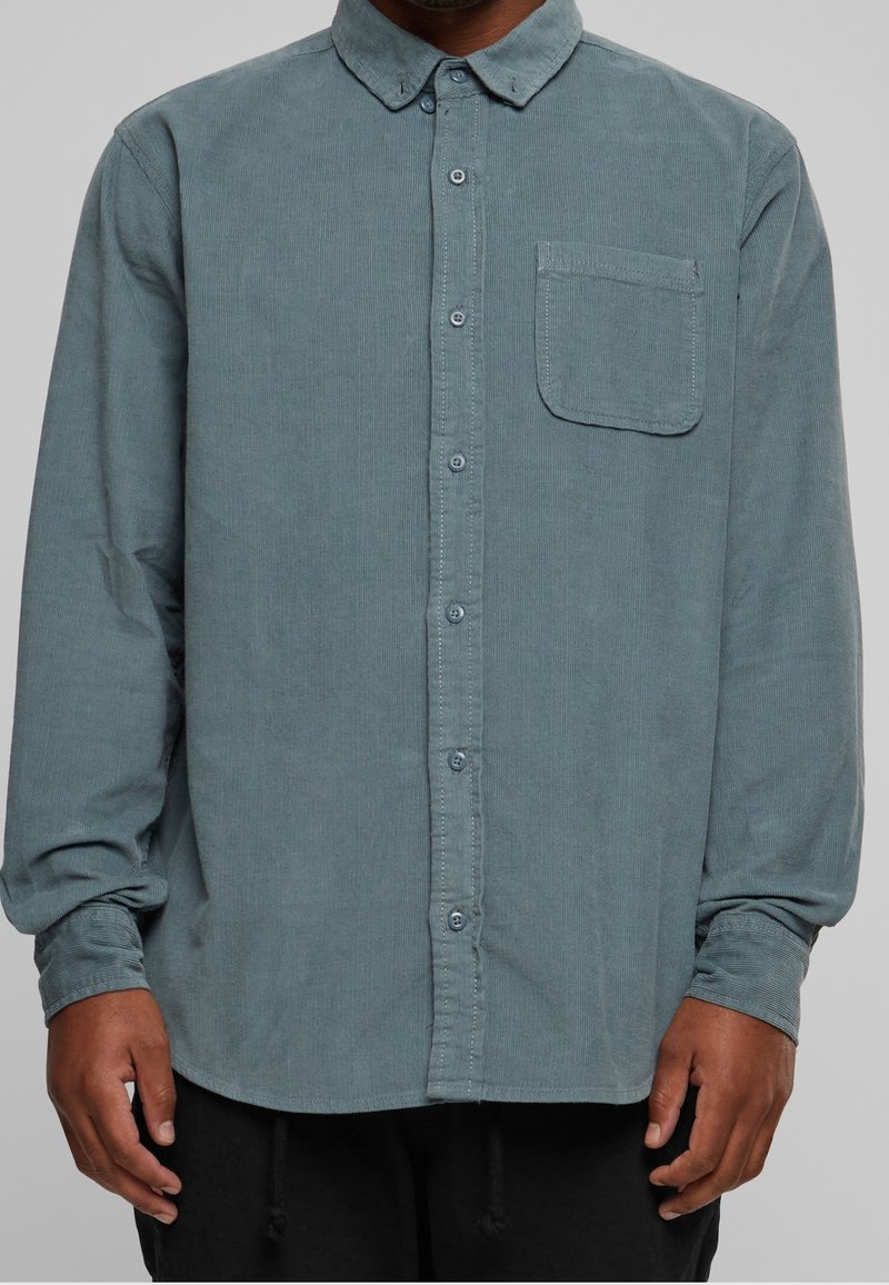Lange mouw button-up shirt in gedempt teal corduroy, met een enkele borstzak, een button-down kraag en subtiele ribbelstructuur.