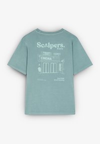 T-shirt en coton bleu ciel avec un imprimé graphique d'un cinéma au dos, avec un texte pour une grande ouverture en encre blanche. Manches courtes.