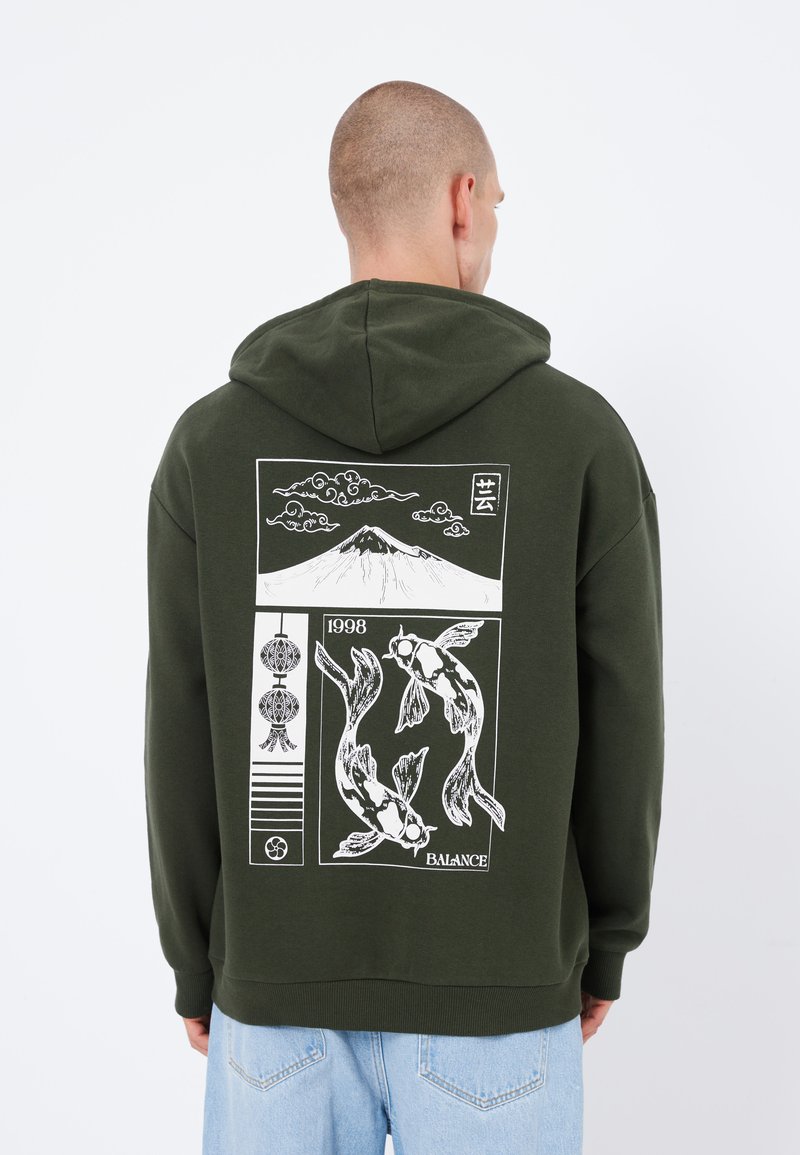 Sweat à capuche vert en coton avec un motif arrière représentant des poissons koi, une montagne et des éléments décoratifs. Design à capuche avec des poignets côtelés.