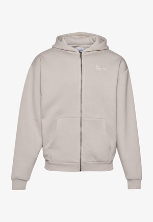 Lys grå zip-up hoodie lavet af blødt stof, med en frontlomme, ribbede manchetter og et lille hvidt logo på brystet.