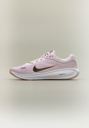 Jasnoróżowy but do biegania Nike z czarnym i złotym logo, białą amortyzowaną podeszwą ComfiRide i brązową podeszwą zewnętrzną na neutralnym tle.
