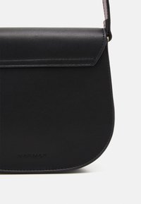 Borsa a tracolla in pelle nera con forma curvata, dotata di chiusura a pattina e logo in rilievo. Texture liscia con dettagli di cucitura minimi.