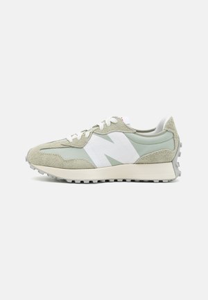 Buty sportowe w jasnozielonym zamszu i siateczce, z kontrastowym białym logo po boku, okrągłymi sznurówkami i teksturowaną szaro-rubberową podeszwą.
