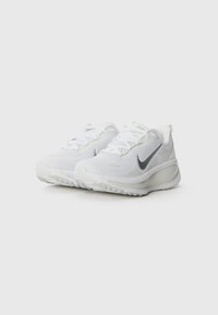Baskets blanches de sport avec une tige en mesh, des accents gris et une semelle rembourrée. Présente un bout arrondi et un logo contrasté sur le côté.