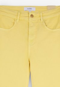 Jeans din denim galben cu închidere frontală cu buton și patru buzunare. Eticheta cu inscripția "SCALPERS" este vizibilă pe talie. Textură netedă.