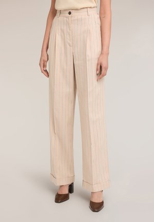 Beige hoge taille wijde broek met dunne verticale strepen, opgerolde zomen, knoopsluiting, gedragen met bruine schoenen met blokhak en puntige neus.