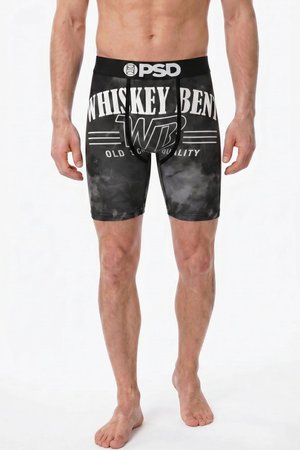 Mężczyzna w czarnych bokserkach z białym tekstem "WHISKEY BENT" i "OLD CHI QUALITY", stojący boso na białym tle.