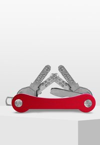 Multi-outil rouge comportant des outils en acier inoxydable, y compris des tournevis plats et Phillips, logés dans un design courbé et ergonomique.