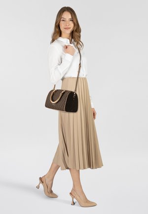 Bruin handtas met patroon, voorzien van dubbele handvatten en een schouderriem. Het model draagt een witte blouse en een beige geplooide rok, gecombineerd met nude hakken.