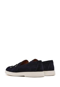 Scarpe slip-on in suede blu navy con suola in gomma bianca contrastante e dettagli di cucitura sottili. Punta arrotondata e texture morbida.