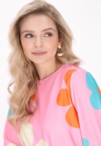 Blusa a fantasia floreale in rosa, con grandi fiori arancioni e turchesi, collo tondo e tessuto morbido.