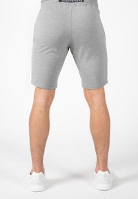 Grijze katoenen shorts met een elastische tailleband met logo, hoog boven de knie gesneden en gecombineerd met witte schoeisel.
