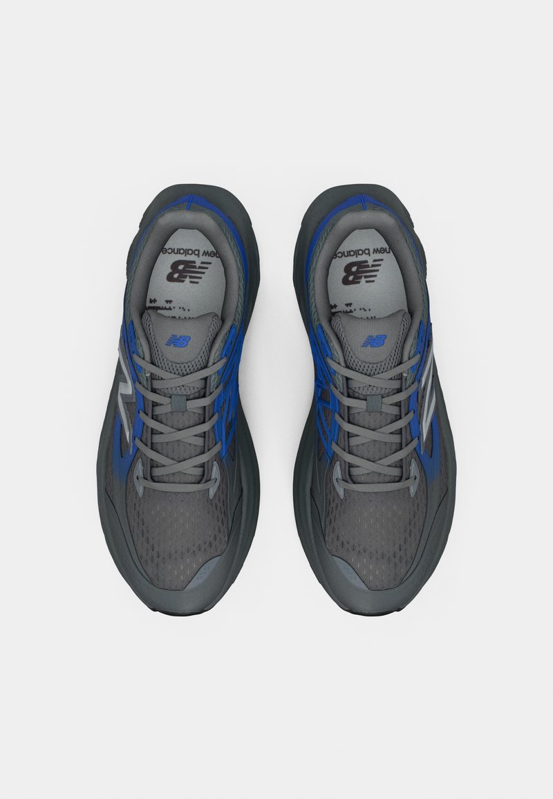 Zapatillas deportivas grises con acentos azules, parte superior de malla texturizada, punta redonda y cordones grises. Presenta un logo en la lengüeta y en el lateral.