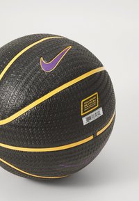Zwarte basketbal met een gestructureerd oppervlak, voorzien van een paarse Nike-logo en gele strepen. Inclusief een label met maat- en barcodegegevens.