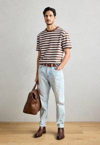 Brun og hvit stripete kortermet skjorte, lyseblå jeans, brun lærbelte, brun lærveske, ankellange brune støvler.