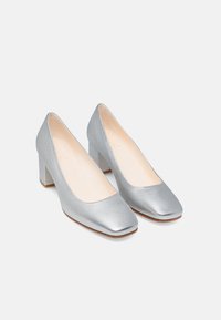 Chaussures à talons hauts en métal argenté avec un bout carré, texture lisse et talon bloc chunky, mettant en avant un design minimaliste.