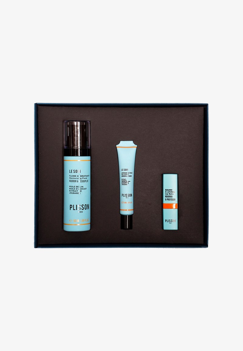 Drei Hautpflegeprodukte in hellblauem Verpackungsdesign werden in einer braunen Box präsentiert. Die größte Flasche ist zylindrisch, die anderen sind konische Tuben.