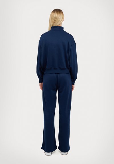Navy blue matching sweatshirt and pants set in soft fabric. Sweatshirt features a high neck, and pants have a flared hem and elastic waistband.