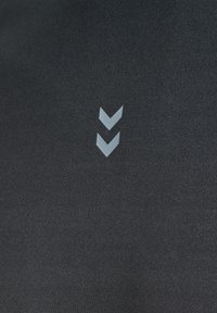 Sort tekstil med en glat struktur har et gråt chevron-logo design, tydeligt placeret i midten.