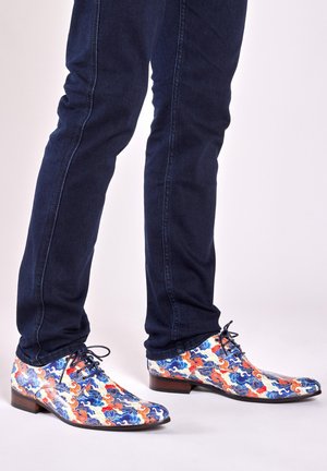 Kleurige schoenen met een golfpatroon, in blauw, rood, wit en oranje. Ze hebben een puntige neus en een donkerbruine leren hak.