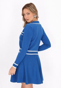Vestido azul hecho de tejido de punto texturizado, con un top ajustado, falda acampanada y rayas blancas horizontales en el cuello y la cintura.