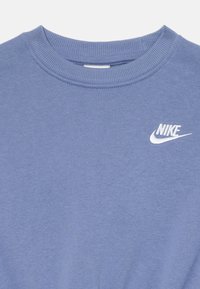 Ανοιχτό μπλε φούτερ με ribbed λαιμόκοψη. Διαθέτει το λευκό λογότυπο της Nike στο αριστερό στήθος. Φτιαγμένο από μαλακό, υφασμένο ύφασμα.