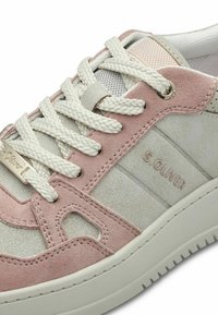 Sneakers en daim rose clair et blanc avec une surface texturée, bout rond, lacets crème et logo sur le côté. Soulignés par un design découpé.