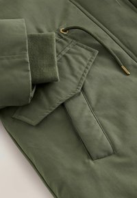 Olivengrüne Jacke aus strukturiertem Stoff, mit elastischen Bündchen, einer Kordel mit goldfarbenen Beschlägen und einem Design mit aufgesetzter Tasche.