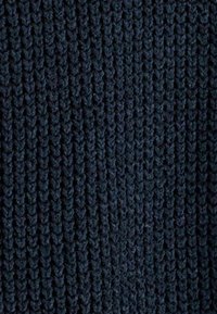 Gros plan sur un tissu tricoté bleu marine foncé avec un motif à texture côtelée vertical.