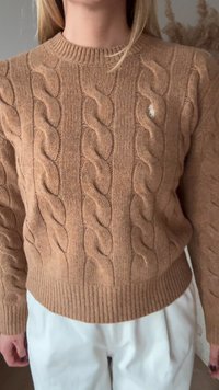 Καφέ πουλόβερ πλεκτό με περίγραμμα στο τελείωμα και τις μανσέτες. Διαθέτει μικρό λογότυπο, με υφή απαλή και ζεστή. Συνδυάζεται με ανοιχτόχρωμο παντελόνι.