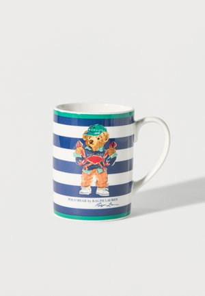 Valge keraamiline kruus siniste ja valgete triipudega, millel on rohelise nokamütsiga karu ja punaseid krabisid hoidva kujutisega ning tekst "Polo Bear by Ralph Lauren".