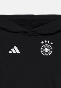Μαύρη φούτερ μπλούζα με κουκούλα από μαλακό ύφασμα, με λευκό λογότυπο Adidas και κεντημένο σήμα της Γερμανικής Ποδοσφαιρικής Ομοσπονδίας με τέσσερις αστερίσκους.