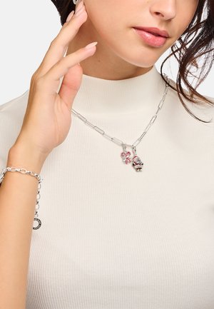 Silver chain necklace with two charms: a red and white striped candy cane and a small bear with embellishments. Smooth, shiny finish.