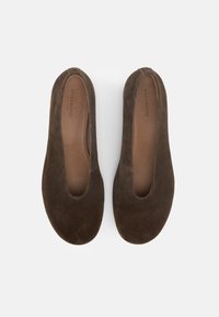 Ζεύγος καφέ σουέτ μπαλαρίνες χωρίς κορδόνια με στρογγυλεμένες μύτες και ταμπά δερμάτινες εσωτερικές σόλες, φωτογραφημένες από πάνω σε λευκό φόντο.